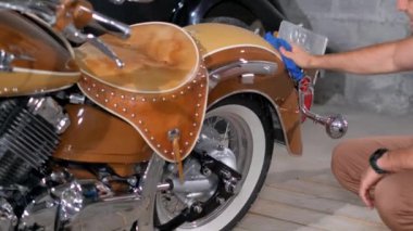 Bir kişi garajda bir motorlu aracın detaylarını anlatıyor, tekerleklere, lastiklere ve çamurluklar ve kaput gibi otomotiv tasarımı elementlerine odaklanıyor.