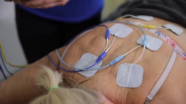 Bir Kadın Sırtında Elektrikli Pedlerle Yatarken Elektrot Masaj Tedavisi Görüyor — Stok video