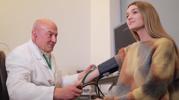 家族の医者と約束した少女 高齢の医師は 血圧をステートスコープで測定する ユースヘルスケア — ストック動画