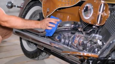 Bir adam motosikletin tekerleklerini ve lastiklerini temizlemek için mavi bir bez kullanıyor. Otomotiv tasarımı ve jantlarıyla ilgilenirken aynı zamanda motorlu taşıtları parlatıyor.