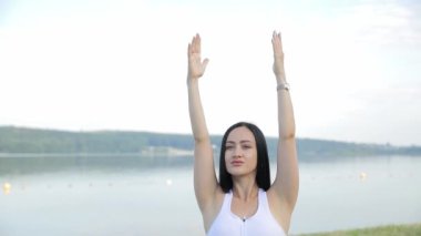 Yoga dersleri sırasında ince, güzel bir esmer. Sabah gölünün arka planında. Yoga temiz havada.