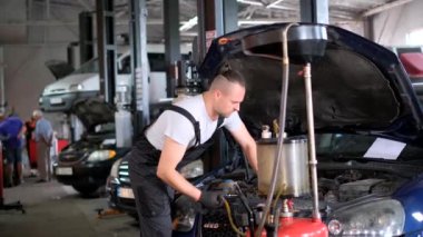 Otomobil tamircisi garajda bir motorlu aracın kaputunun altında çalışıyor, iş kıyafeti giyiyor. Flaş fotoğrafçılık otomotiv mühendisliği sahnesini yakalar