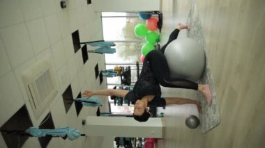 Spor salonunda egzersiz topu ve pilates topuyla egzersiz yapan bir kadın güç, esneklik ve dengeyi gösterir. Buna pilates topunun amuda kalkması da dahil.