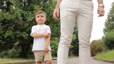 Beyaz tişörtlü şirin bir çocuk babasıyla birlikte parkta yürüyor. Yüksek kalite 4k görüntü