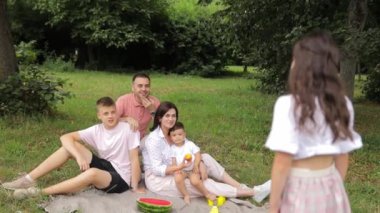 Küçük bir kız büyük ailesi için yaz parkında şarkı söylüyor. Yüksek kalite 4k görüntü