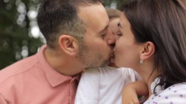 Mutlu ebeveynler küçük oğullarını öper. Yüksek kalite 4k görüntü