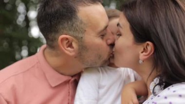 Mutlu ebeveynler küçük oğullarını öper. Yüksek kalite 4k görüntü