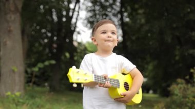 Parkta gitar çalan mutlu küçük çocuk. Yüksek kalite 4k görüntü