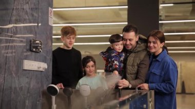 Üç çocuklu genç pozitif bir aile, inşaat süpermarketinde banyo musluğu seçiyor. Modern aksesuarlar ve ev eşyaları koleksiyonu.