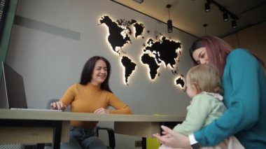 Bir anne ve kızı seyahat acentesinde bir tatil bileti seçiyor. Seyahat kavramı.