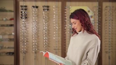 Bir kadın bir optik mağazada oturuyor, etrafı tekstil ve ahşap ile çevrili bir kitap okuyor. Oda görsel sanatlar ve kürk aksanıyla dolu. Bu da kitabının tadını çıkarmayı eğlenceli ve sanatsal bir yer haline getiriyor.