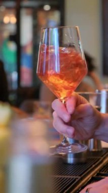 Bir insan, serinletici buz küpleriyle bir bardak şaraptan zevk alır, rahatça soğutulmuş bir içeceğin tadını çıkarır.