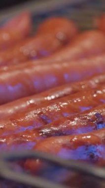 Sulu, kahverengi sosislerin yakın plan çekimleri yapılıyor. Barbekü. Mutfak spatulasıyla sosis pişirmek. Izgara et.
