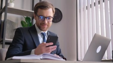 Takım elbiseli bir adam bilgisayarlı ve cep telefonlu bir adam, dijital olarak çalışırken odak ve meşguliyetini gösteriyor.