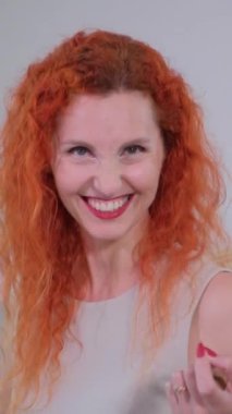 Kızıl saçlı neşeli bir kadın bir madeni para sergiliyor. Değerini simgeliyor. Aynı zamanda seyircilere gülümsemesini gösteriyor. Bir ruj sunuyor, yaratıcılığı ve gücü somutlaştırıyor.