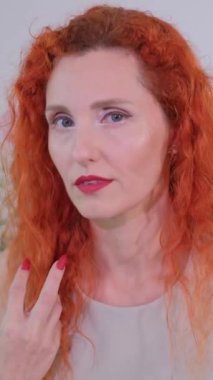 Bu çekici videoda, kendine güvenen kızıl saçlı ve tırnaklı bir kadın kendini ifade ediyor, doğrudan göz teması kuruyor, ve cesur tarzını sergiliyor.