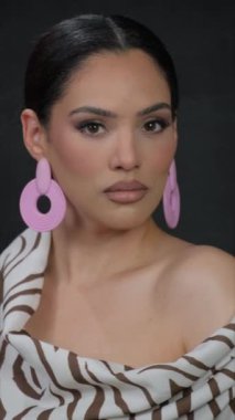 Zebra desenli elbiseli ve kalın pembe küpeli şık bir kadın dikkat çekiyor. Kendine güvenerek, eşsiz moda anlayışını sergiliyor.