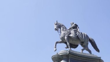 Etkileyici bir heykel, güçlü bir atın üzerinde mavi gökyüzüne karşı bir adam tasvir ediyor. Gücün, cesaretin, liderliğin ve hayvanlarla olan bağın sembolü.