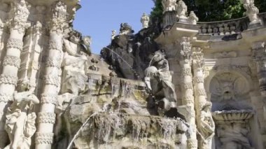 Bu video zarif bir binanın önünde muhteşem bir çeşme ve heykellerle çarpıcı bir mimari manzara sergiliyor.