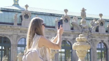 Bu dinamik videoda, genç bir kadın cep telefonuyla şehir macerasını yakalıyor, ikonik bir dönme dolabın ve çarpıcı bir mimarinin fotoğraflarını çekiyor.