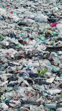 Dikey video. Çöp sahasındaki çöp yığınına yakın çekim. Atık işleme sorunu. İnsan aktivitesi israfı