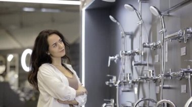 Bir kadın hırdavatçıda duş başlığını seçer. Banyo için yüksek kaliteli aksesuarlar.