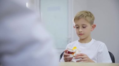 Rahat bir yerde, genç bir çocuk düşünceli aktiviteleri keşfediyor hapları, model bir dişi inceliyor, sağlığı yansıtıyor ve kahveyi yudumluyor.