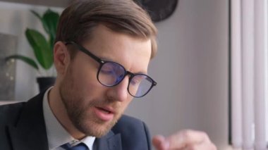 Takım elbiseli yorgun bir işadamı, yoğun bir iş gününde stresli ve bitkin görünüyor, yakın çekimlerde, öksürük, esneme, gözlerini ovuşturma, ve bir cep telefonuyla konuşma