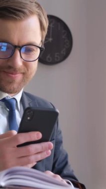 Takım elbiseli bir adam bilgisayarlı ve cep telefonlu bir adam, dijital olarak çalışırken odak ve meşguliyetini gösteriyor..