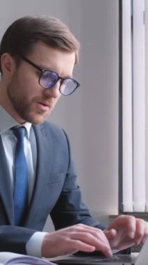 Takım elbiseli bir profesyonel, görevini yaparken motivasyon ve kararlılığı somutlaştıran bir dizüstü bilgisayarla çalışma masasında özenle çalışır..