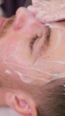 Kaplıca salonunda yüz masajı yaptıran genç bir adam. Profesyonel masaj..