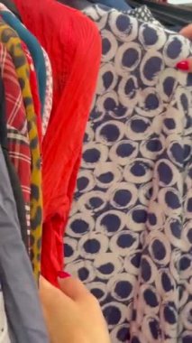 Askılarda kullanılmış giysiler seçen kadın ellerinin yakın çekimi. İkinci el. Yoksulluk. Kara Cuma