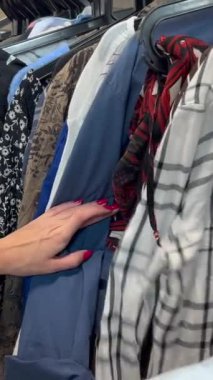 Uzun saçlı genç bir kadın bir giyim mağazasından kullanılmış giysiler alır. Bir kadın kullanılmış giysileri dikkatle inceler. Kara Cuma