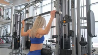 Bu fitness videosunda kendini adamış bir kadın modern bir spor salonunda çeşitli egzersizler sergiliyor.