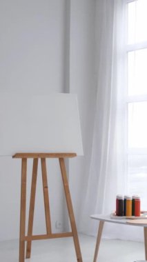 Dikey video. Beyaz tonlarda yaratıcı sanat atölyesi. Yaratıcı bir atölyenin içinde. Modern minimalist beyaz stilinde bir atölye çalışması