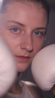 Boks eldivenli genç bir kadının yüzünü yakından çek. Kadın boksör. Bir spor kadının portresi. Dikey video