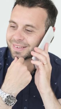 Siyah gömlekli, telefonda konuşan çekici bir gencin yakın plan portresi. Beyaz arka planda neşeli esmer bir adam telefonda konuşuyor..