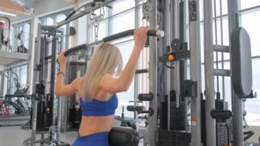Bu fitness videosunda kendini adamış bir kadın modern bir spor salonunda çeşitli egzersizler sergiliyor.