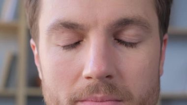 Bir adamın yakın çekimleri gözlerini kapatır, sonra mavi gözlerini ve sakalını gösterir. Son çekim onun yoğun mavi gözlerini doğrudan kameraya bakarak yakalıyor.