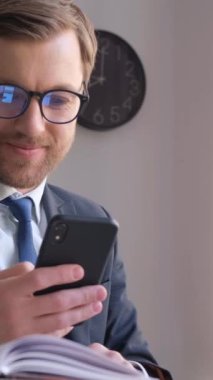 Takım elbiseli bir adam bilgisayarlı ve cep telefonlu bir adam, dijital olarak çalışırken odak ve meşguliyetini gösteriyor..