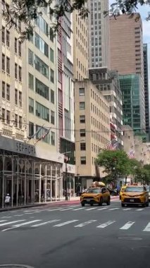 Yükselen gökdelenlerden geçen, hareketli şehir atmosferini ve dinamik trafik akışını vurgulayan sarı taksilerle dolu bir şehir caddesi.