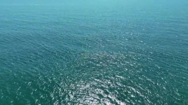 Bu video, berrak mavi gökyüzünü yansıtan ve dingin bir atmosfer yaratan uçsuz bucaksız bir su kütlesinin nefes kesici bir görüntüsünü sunuyor.