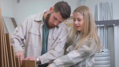 Bir adam ve bir kadın oturmuş, bir yığın karton yığına bakarken eğlenceli bir anı paylaşıyorlar. Hareketlerine bakılırsa bir inşaat projesini tartışıyorlar ya da yaklaşan bir etkinliği planlıyorlar.