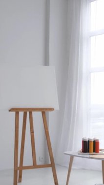 Dikey video. Beyaz tonlarda yaratıcı sanat atölyesi. Yaratıcı bir atölyenin içinde. Modern minimalist beyaz stilinde bir atölye çalışması