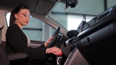 Güzel bir kadın araba galerisinde yeni arabasında oturuyor. Yüksek kalite 4k görüntü