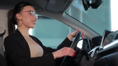 Gözlüklü genç bir kadın bir arabada oturur ve arabanın içini inceler. Yüksek kalite 4k görüntü