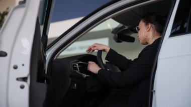 Yeni bir arabanın içinde otururken direksiyonu tutan takım elbiseli çekici bir kadın. Sürüş, ulaşım konsepti. Yüksek kalite 4k görüntü