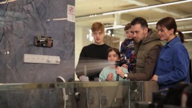 Genç ve dost canlısı bir aile, ev eşyaları satan bir dükkanda banyo musluğu seçiyor. Hırdavatçıdaki banyo muslukları da dahil. Tercih. Alışveriş.