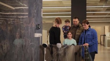 İnşaat süpermarketinde banyo ve duş için mikser denerken mutlu pozitif aile. Ev için hijyenik malzeme seçmek