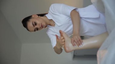 Masaj ustası iki eliyle kadın ayağını yoğuruyor. Vücut bakımı konsepti. Yüksek kalite 4k görüntü